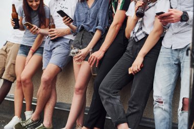 Ellerinde alkol ve telefonlarla dikiliyorsun. Gündelik giysiler içinde bir grup genç gündüz vakti çatıda parti veriyor..