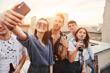 Selfie çekiyorum. Güzel güneş ışığı. Gündelik giysiler içinde bir grup genç gündüz vakti çatıda parti veriyor..