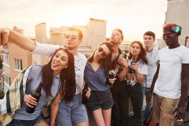 Selfie çekiyorum. Güzel güneş ışığı. Gündelik giysiler içinde bir grup genç gündüz vakti çatıda parti veriyor..