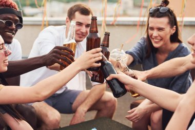 Oyun oynayıp masanın başında oturmak. Gündelik giysiler içinde bir grup genç gündüz vakti çatıda parti veriyor..