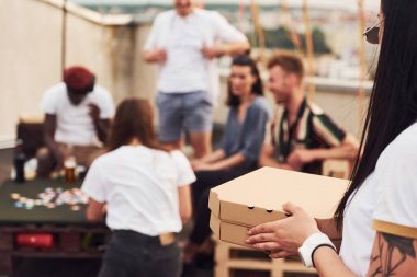 Oyun oynayıp masanın başında oturmak. Gündelik giysiler içinde bir grup genç gündüz vakti çatıda parti veriyor..
