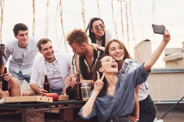 Fotoğraf çekiyorum. Lezzetli pizza. Gündelik giysiler içinde bir grup genç gündüz vakti çatıda parti veriyor..