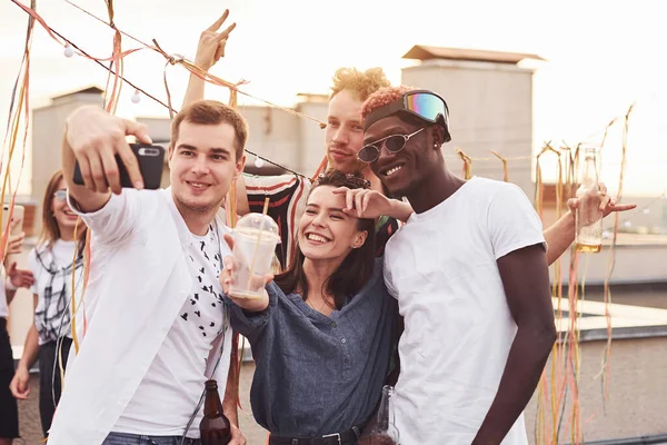 Birlikte durup selfie çekiyoruz. Gündelik giysiler içinde bir grup genç gündüz vakti çatıda parti veriyor..