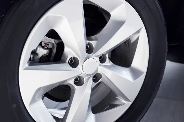 Close up view of automobile's wheel. Brand new car parked indoors.