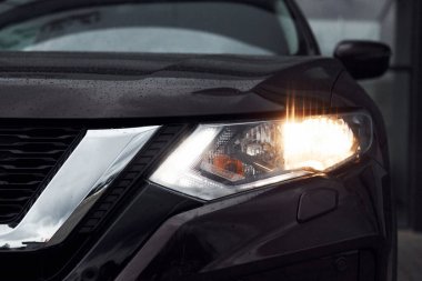 Ön parçacık görünümü siyah modern otomobilin farları açık.