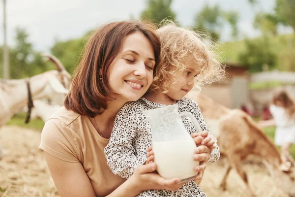 Fresh natural milk. Young mother with her daughter is on the farm at summertime.