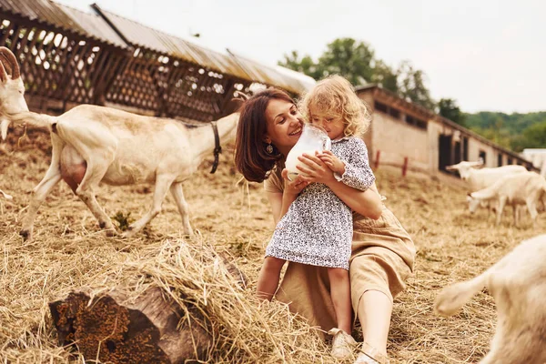 娘と一緒に若い母親はヤギと夏に農場にいます — ストック写真