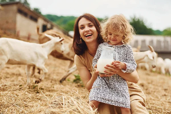 Fresh natural milk. Young mother with her daughter is on the farm at summertime with goats.