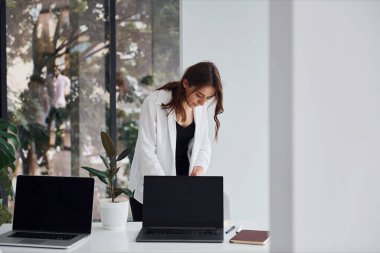 Resmi giyinmiş genç beyaz kız gündüz vakti ofiste olur..