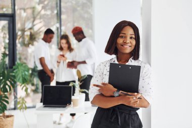 Elinde not defteri olan bir kadın. Bir grup Afro-Amerikan iş adamı birlikte çalışıyor..