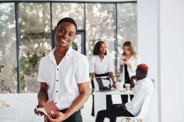 Pozitif adam meslektaşlarının önünde duruyor. Bir grup Afro-Amerikan iş adamı birlikte çalışıyor..