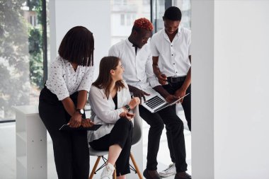 Meşgulüm, dizüstü bilgisayarım ve not defterim var. Bir grup Afro-Amerikan iş adamı birlikte çalışıyor..