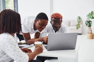 Dizüstü bilgisayar kullanarak projeye odaklanmış. Bir grup Afro-Amerikan iş adamı birlikte çalışıyor..