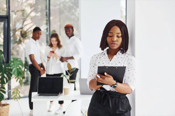 Woman holding notepad. Group of african american business people working in office together.