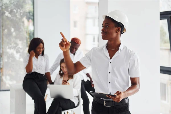 Engineer in hardhat. Group of african american business people working in office together.