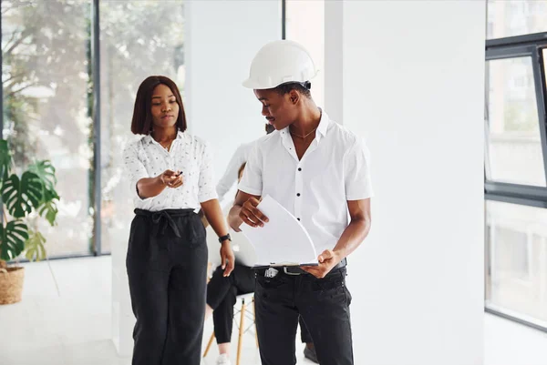 Engineer in hardhat. Group of african american business people working in office together.