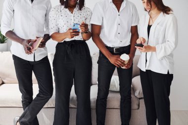 Bir grup Afrikalı Amerikalı resmi giysiler içinde ofiste koltuğun yanında birlikte duruyorlar..