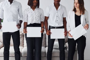 Resmi giyinmiş bir grup Afrikalı Amerikalı ofiste koltuğun yanında el ele tutuşup boş kağıtları tutuyorlar..