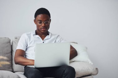 Kapalı mekanda dizüstü bilgisayarı olan, resmi giyinmiş genç Afro-Amerikan bir adam..