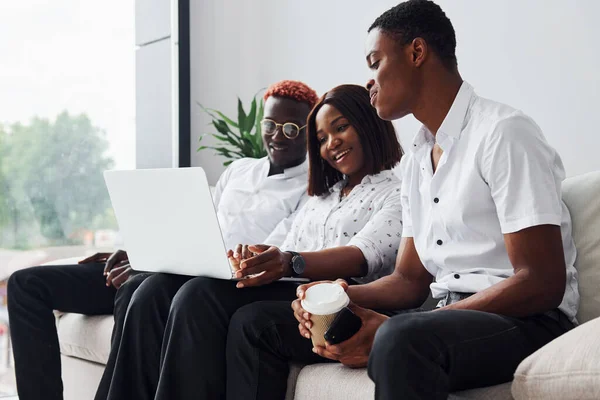 Comfortable sofa. Using laptop. Group of african american business people working when sitting together.