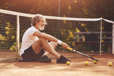 Oturup ara veriyoruz. Beyaz gömlekli ve tenis kortunda siyah şortlu son sınıf stil sahibi bir adam..