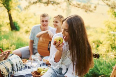 Kadın elma yiyor. Bir grup gencin dışarıda, ormanda tatili var. Hafta sonu ve arkadaşlık kavramı.