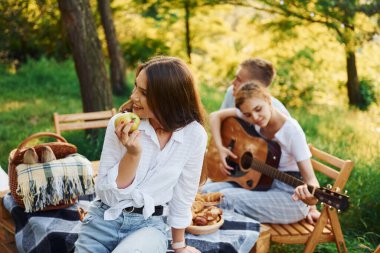 Kadın elma yiyor. Bir grup gencin dışarıda, ormanda tatili var. Hafta sonu ve arkadaşlık kavramı.