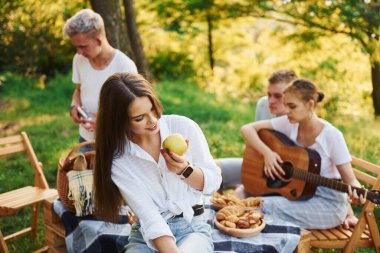 Kadın elma yiyor. Bir grup gencin dışarıda, ormanda tatili var. Hafta sonu ve arkadaşlık kavramı.