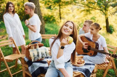 Kadın elma yiyor. Bir grup gencin dışarıda, ormanda tatili var. Hafta sonu ve arkadaşlık kavramı.