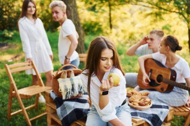 Kadın elma yiyor. Bir grup gencin dışarıda, ormanda tatili var. Hafta sonu ve arkadaşlık kavramı.
