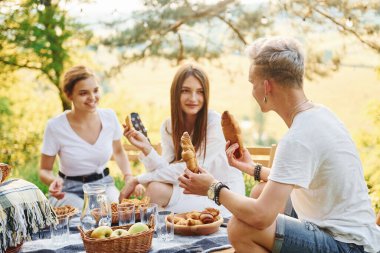 Piknik masasında oturuyor. Bir grup gencin dışarıda, ormanda tatili var. Hafta sonu ve arkadaşlık kavramı.