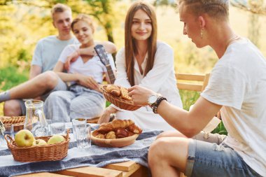 Piknik masasında oturuyor. Bir grup gencin dışarıda, ormanda tatili var. Hafta sonu ve arkadaşlık kavramı.