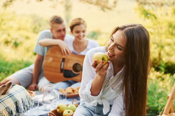 Kadın elma yiyor. Bir grup gencin dışarıda, ormanda tatili var. Hafta sonu ve arkadaşlık kavramı.