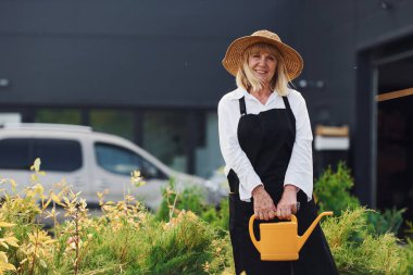 Çiçekleri sulamak. Sunbae gündüz vakti bahçede..