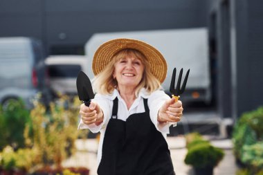 Aletleri tutuyorum. Kıdemli kadın gündüz vakti bahçede olur. Bitki ve mevsim kavramı.