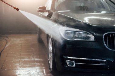 Yüksek basınçlı su. Modern siyah otomobil oto yıkama istasyonunda temizlenir..