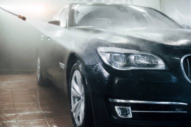 Yüksek basınçlı su. Modern siyah otomobil oto yıkama istasyonunda temizlenir..