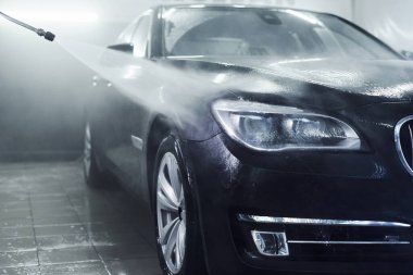 Yüksek basınçlı su. Modern siyah otomobil oto yıkama istasyonunda temizlenir..