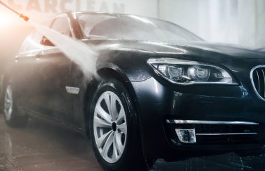 Yüksek basınçlı su. Modern siyah otomobil oto yıkama istasyonunda temizlenir..