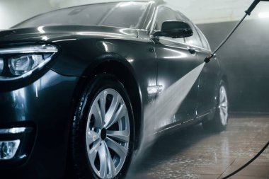 Yüksek basınçlı su. Modern siyah otomobil oto yıkama istasyonunda temizlenir..