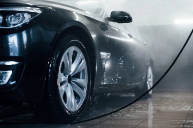 Yüksek basınçlı su. Modern siyah otomobil oto yıkama istasyonunda temizlenir..