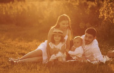 Çimlerin üzerinde oturuyordum. Baba, anne ve kız ve oğul yazın güneşli bir gününde dışarıda vakit geçiriyorlar..
