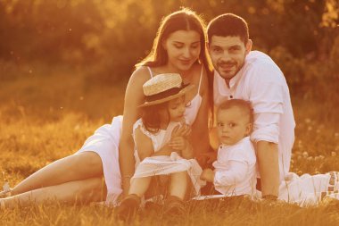 Çimlerin üzerinde oturuyordum. Baba, anne ve kız ve oğul yazın güneşli bir gününde dışarıda vakit geçiriyorlar..