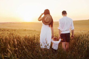 Anne ve baba oğullarıyla güneşli yaz günlerinde boş zamanlarını sahada geçiriyorlar. Arkadan görüntüle.