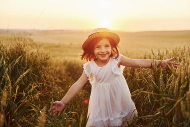 Yazın tarlada koşan beyaz elbiseli neşeli küçük kız..