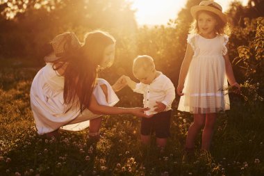 Neşeli anne, küçük oğul ve kız çocukları yazın güneşli bir gününde boş zamanlarını sahada geçirirler..