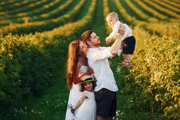 Father, mother with daughter and son spending free time outdoors at sunny day time of summer.