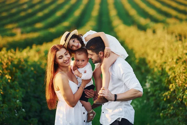 At agricultural field. Father, mother with daughter and son spending free time outdoors at sunny day time of summer.