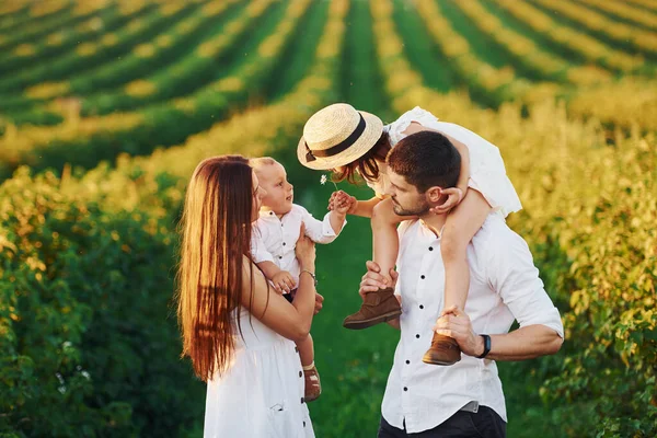 At agricultural field. Father, mother with daughter and son spending free time outdoors at sunny day time of summer.