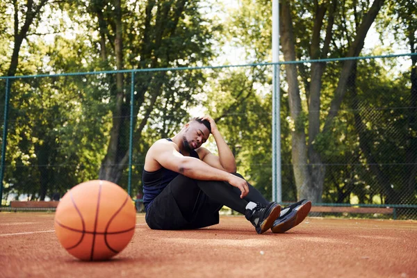 Κουρασμένος Αφροαμερικάνος Κάθεται Στο Έδαφος Μπάλα Στο Γήπεδο Έξω Κάνει — Φωτογραφία Αρχείου